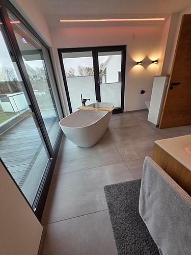 Modernes Badezimmer mit freistehender Badewanne als Beispiel für präzise Detailplanung und Materialwahl im Bauwesen.