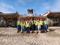 Exkursion Bautechniker 11 09 Gruppe mit Schutzhelmen und Warnwesten steht in der Schaufel eines riesigen Radladers bei einer Exkursion.