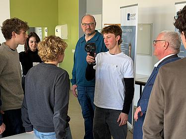 Mehrere Schüler beobachten einen Mitschüler bei der Nutzung einer Wärmebildkamera im Unterricht.