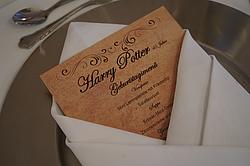 Nahaufnahme einer Menükarte mit dem Titel „Harry Potter – 45 Jahre“, dekorativ in eine weiße Serviette auf einem Silbertablett gesteckt.