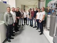 Exkursion Freiburg – Technik hautnah erleben Gruppenfoto von Exkursionsteilnehmenden in einem technischen Ausstellungsbereich mit Maschinen- und Anlagenteilen.