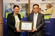 Andrea Radlbeck von den Eckert Schulen und ein Vertreter des Shaanxi Technical College of Finance & Economics präsentieren gemeinsam die gerahmte Tafel „Sino-German Qinling Workshop“ als Zeichen ihrer Bildungspartnerschaft.