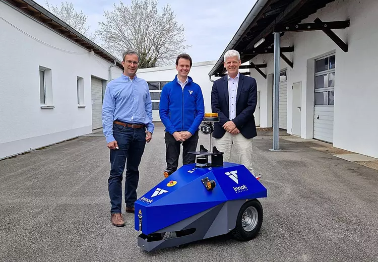 Gruppenfoto mit Roboter in drei Personen im Hintergrund: v.l.n.r.: Herr Brandt und Herr Heerklotz (Innok Robotics) gemeinsam mit Herrn Zimmermann (Schulleiter und Geschäftsführer der Dr. Eckert Akademie)